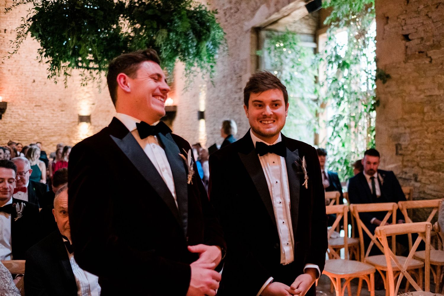 Wedding guests sharing laughter during a celebration in a rustic indoor setting.