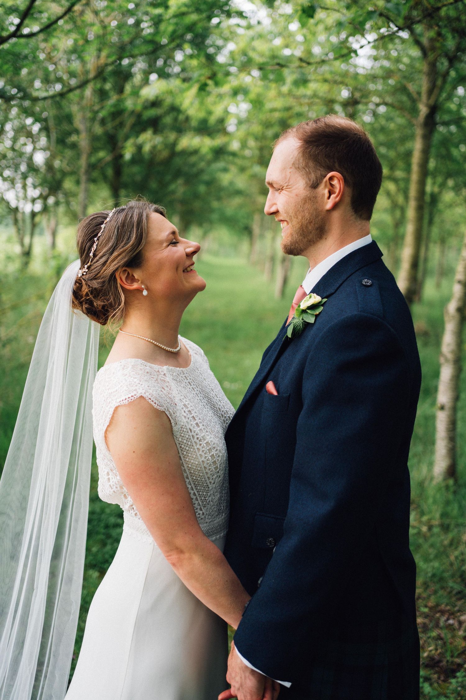 Couple shares romantic moment in wooded setting during wedding portraits.