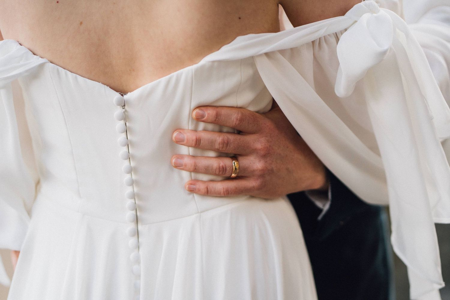 Close-up detail of delicate button closures on a white wedding dress sleeve.