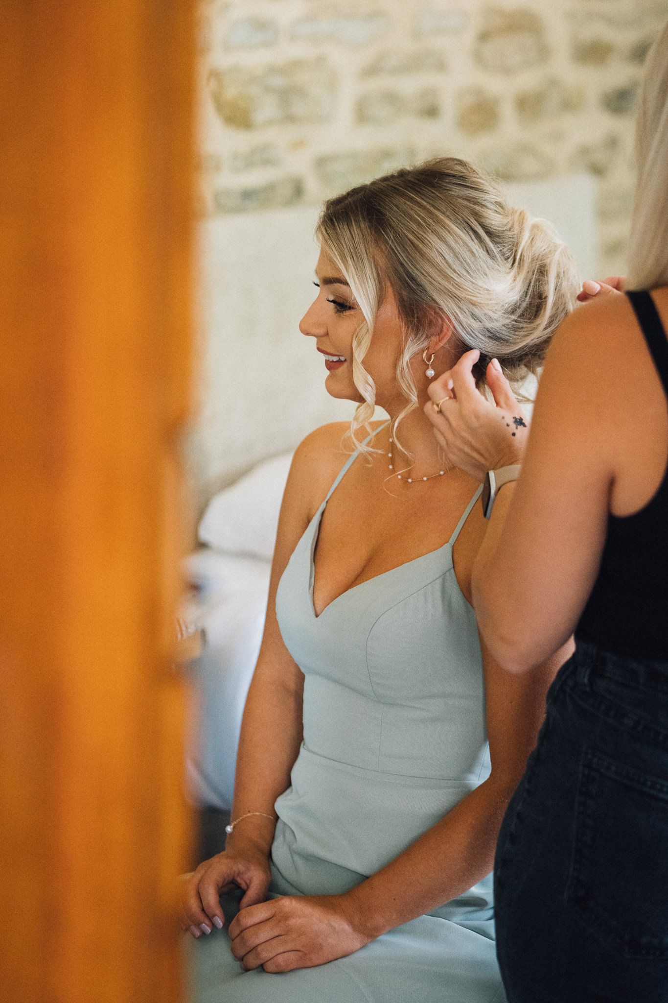 Soft morning light illuminates a wedding preparation scene in a stone-walled room.