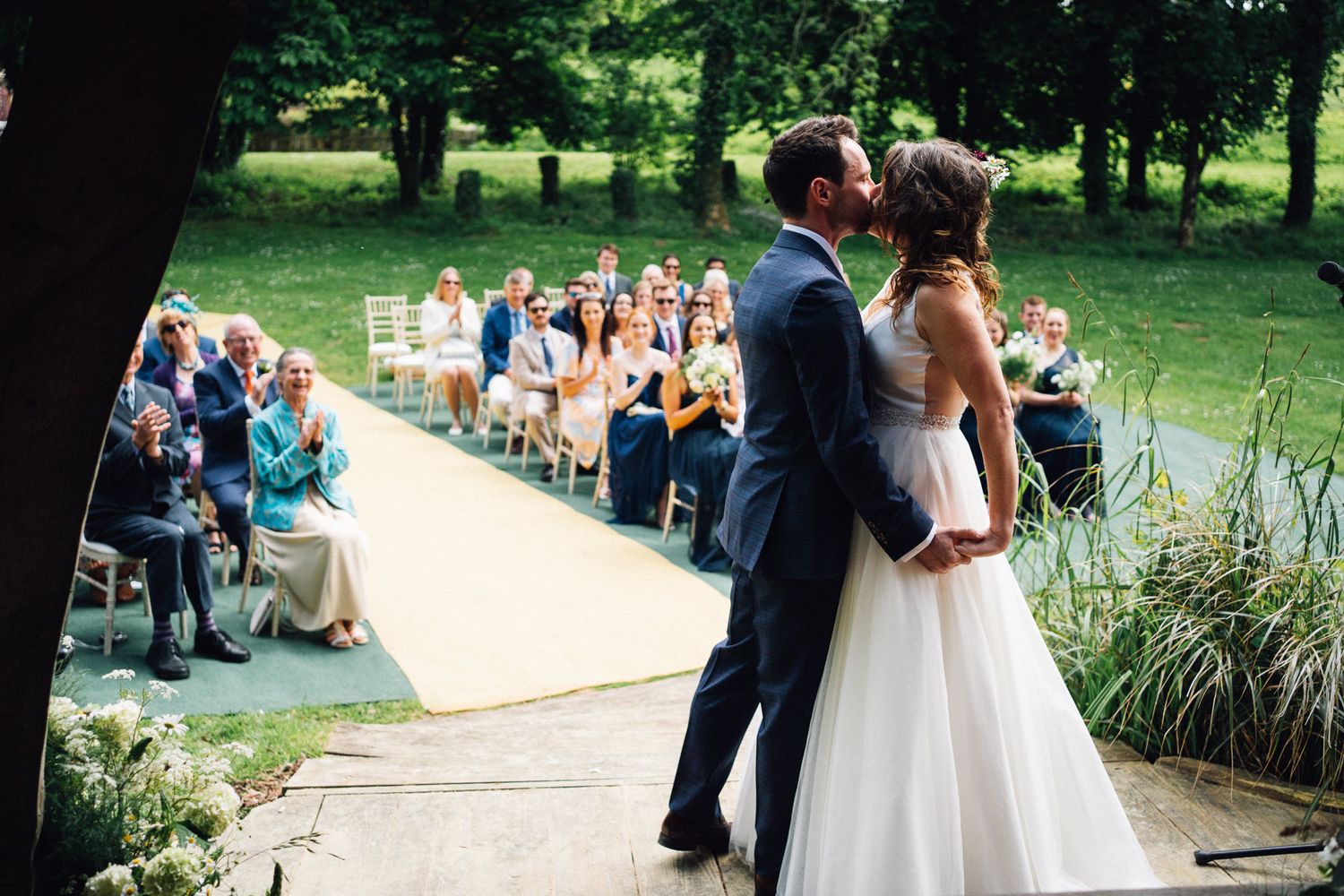 Wedding ceremony setup overlooking a scenic pond with white chairs and natural landscaping.