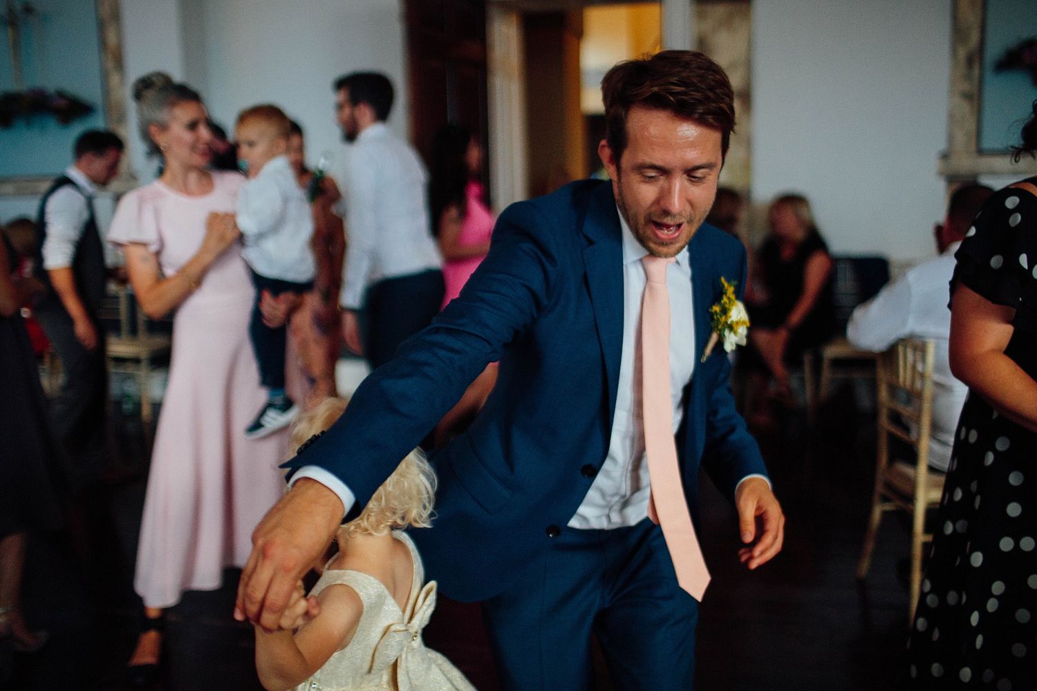 Guests dancing and celebrating at an indoor wedding reception with formal decor.