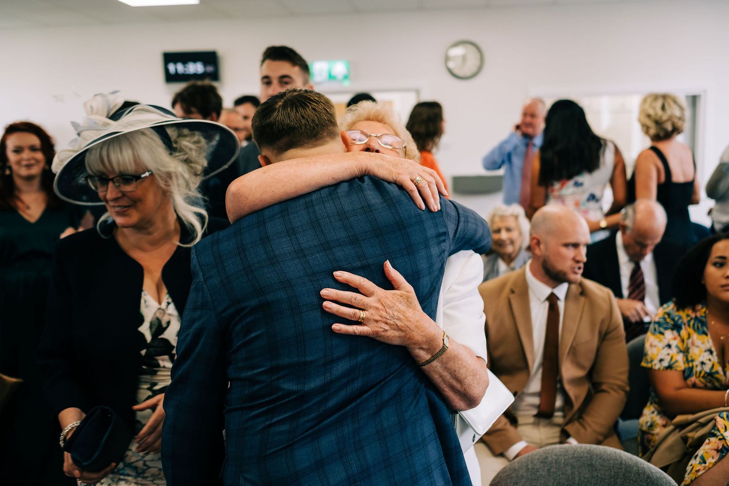 Wedding reception celebration with guests embracing and dancing in an indoor venue.