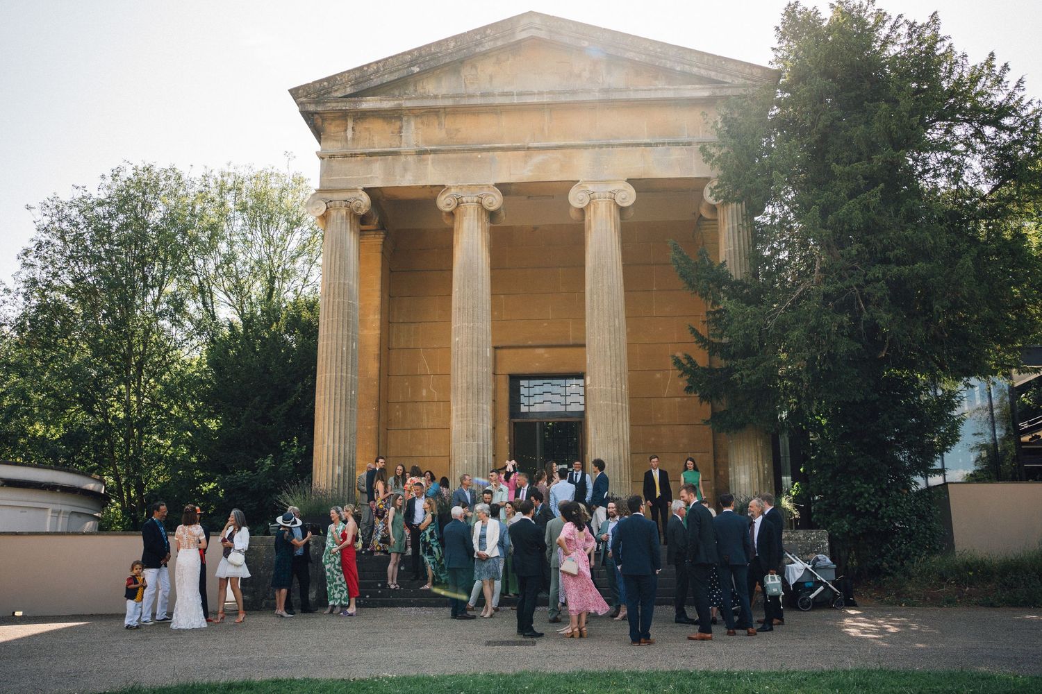 Wedding guests gathered outside a neoclassical building for a group photo.
