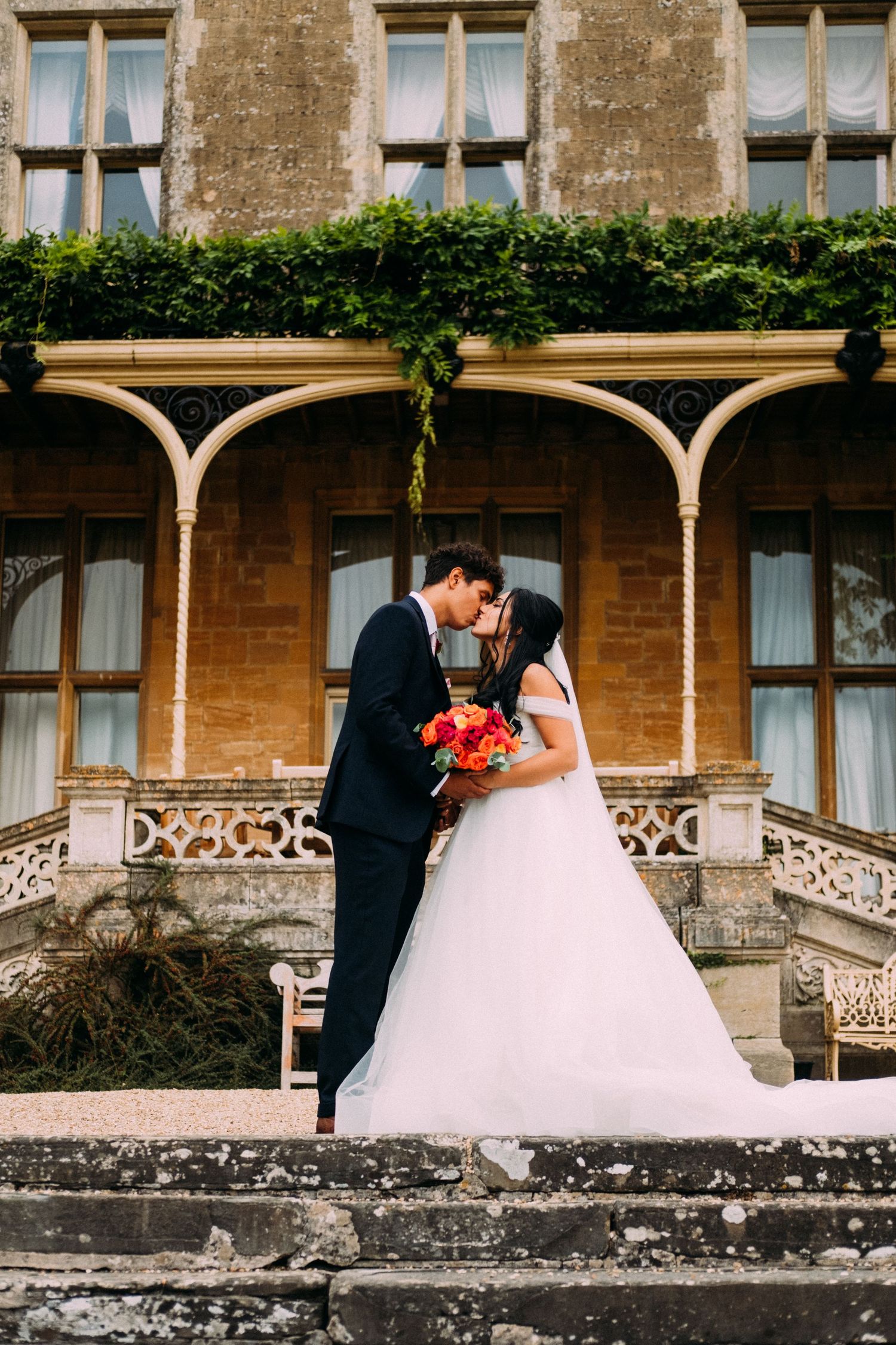 Historic stone mansion with ornate architectural details serves as romantic wedding backdrop.