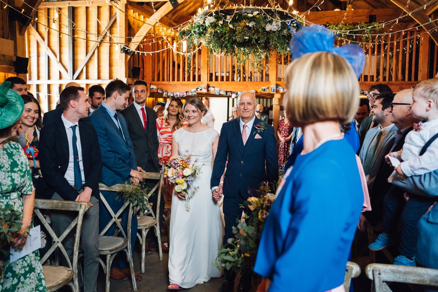 Wedding celebration in a rustic barn venue decorated with string lights and greenery.