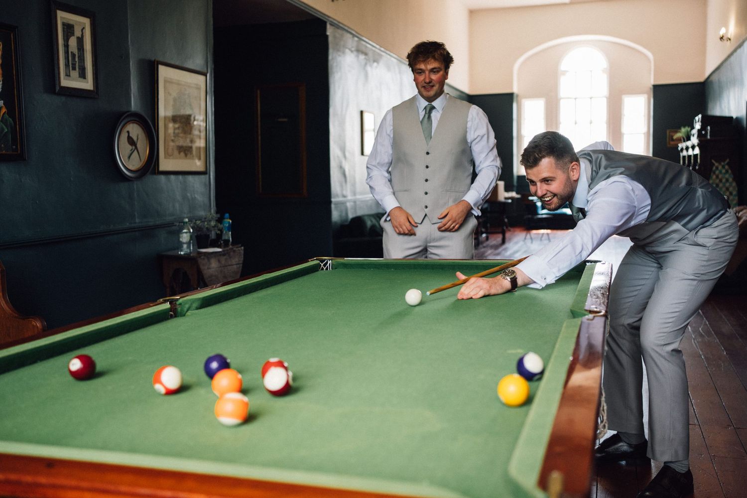 Multiple shots of people playing pool on a green felt table in formal wear.