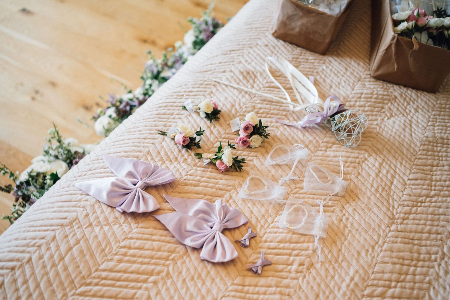 Delicate pink satin fabric bows and floral decorations arranged on a textured white tablecloth.
