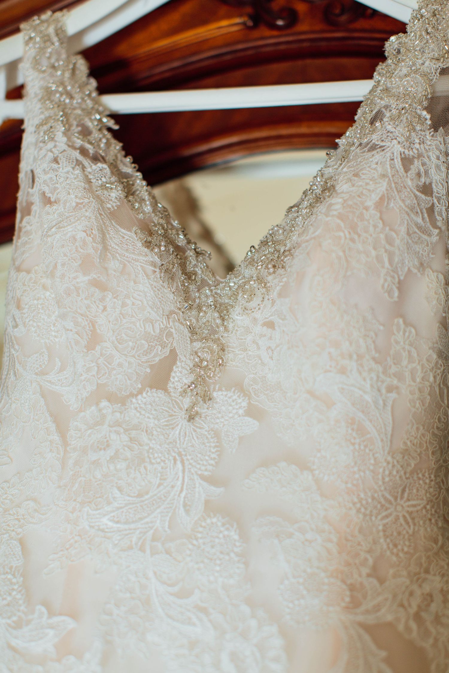 A row of elegant white lace wedding dresses with intricate beading details hanging on display.