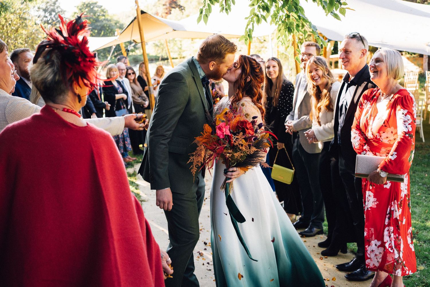 Wedding guests mingle and celebrate at an outdoor reception with string lights and decorative elements.