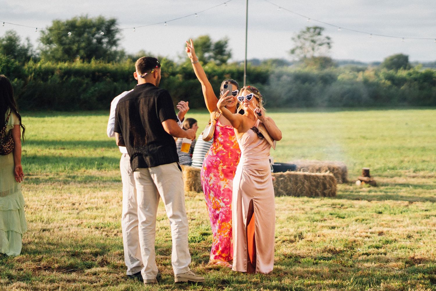 People celebrate joyfully in a golden sunlit field during a summer outdoor event.