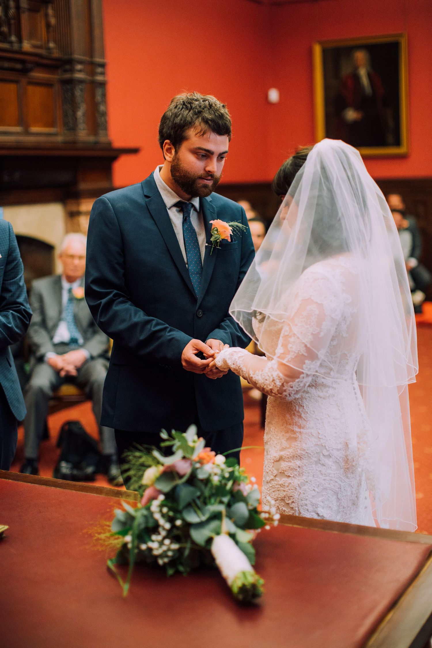 A couple signs their marriage certificate at a wooden table during their wedding ceremony.