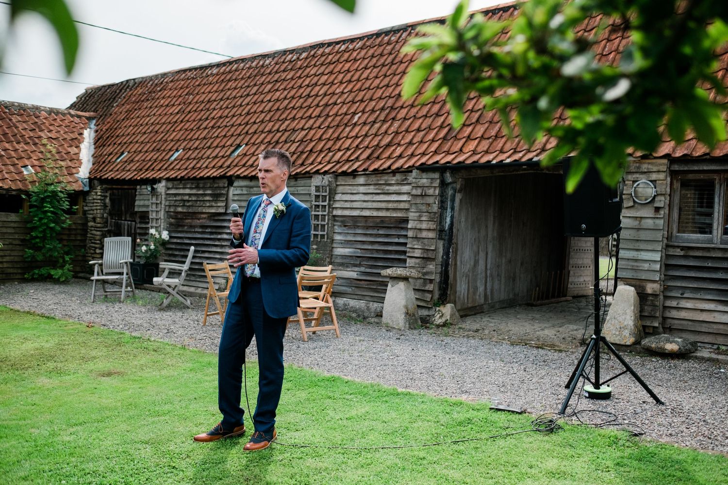 Rustic barn venue with red tile roof and wooden exterior during a countryside wedding.