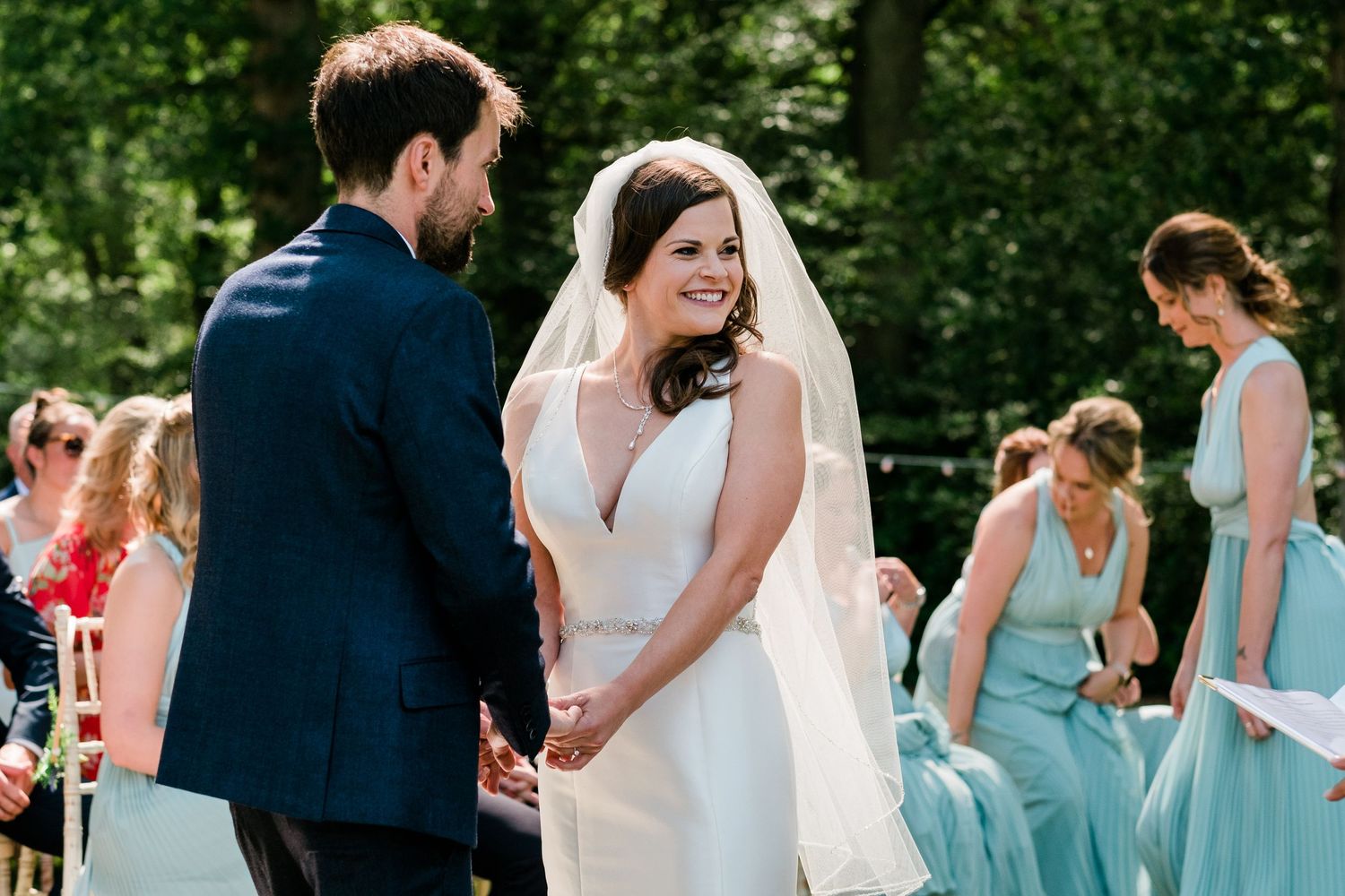Outdoor wedding ceremony with bridesmaids in light blue dresses standing in a row.