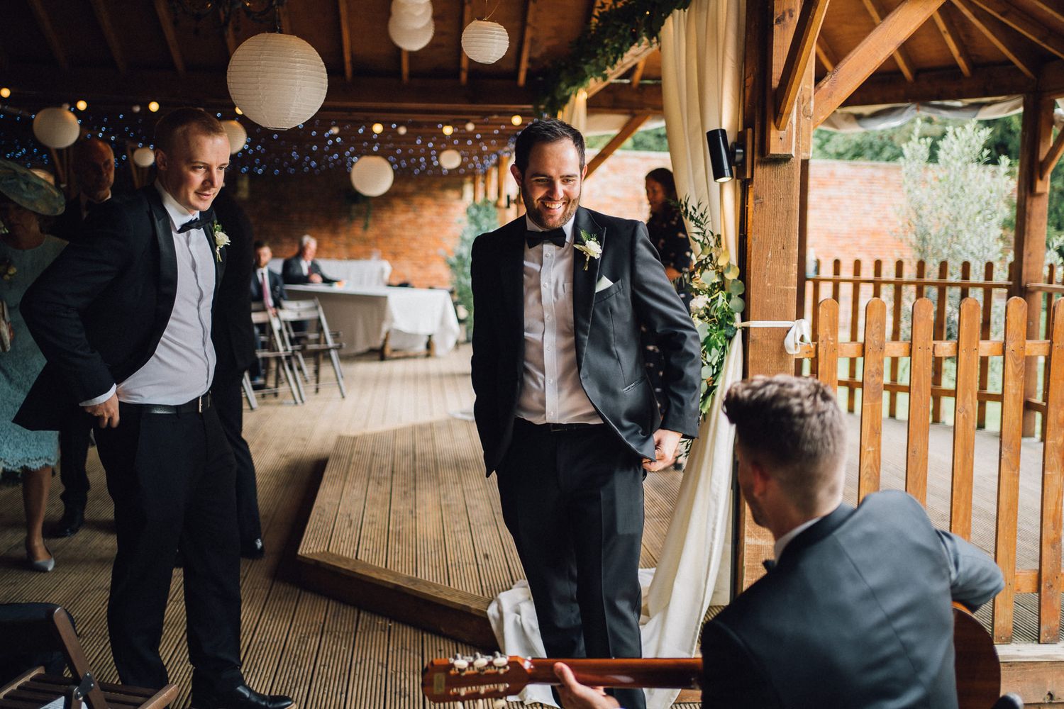 Wedding reception venue with exposed wooden beams and white paper lantern decorations.