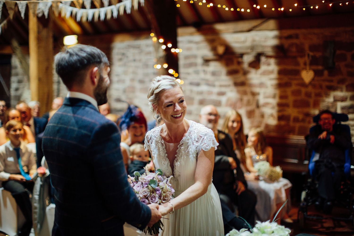 Rustic barn wedding reception with string lights and white bunting decorations.