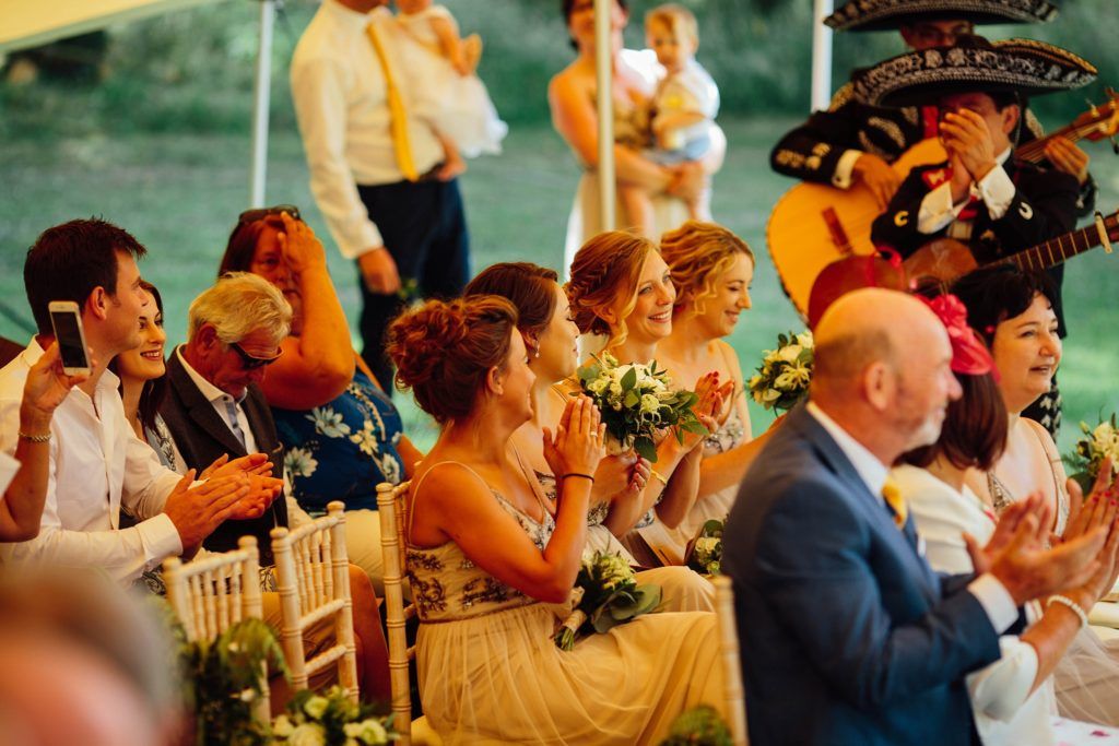 Guests laugh and enjoy entertainment during a festive wedding reception.