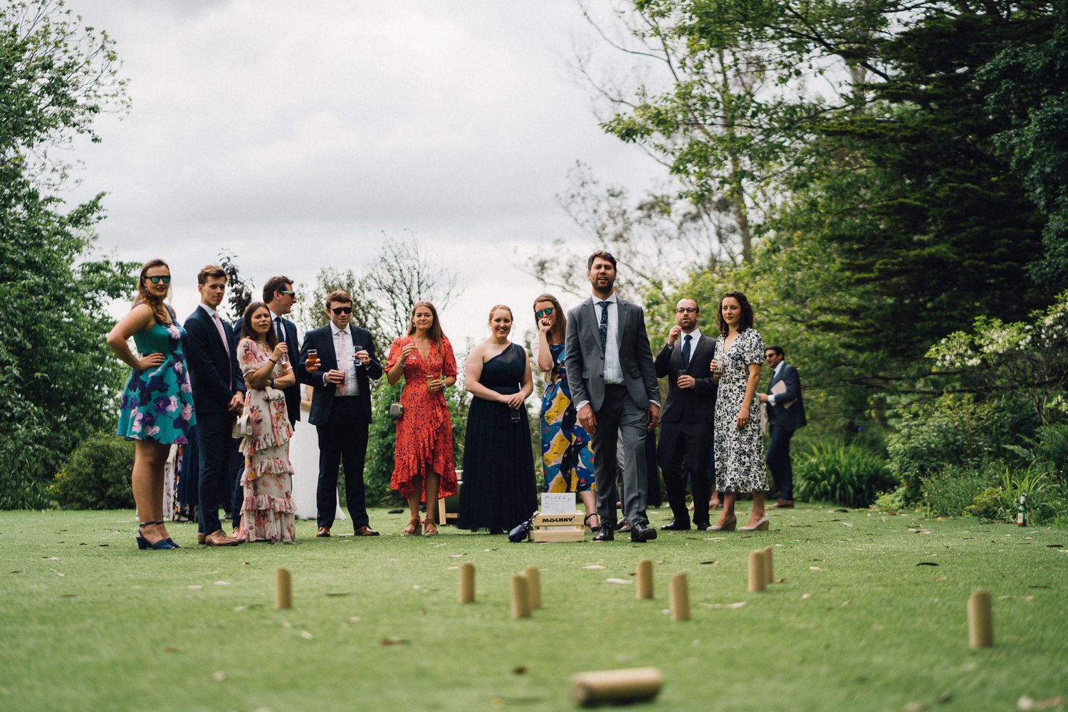 Wedding party and guests participate in outdoor lawn games during garden reception.