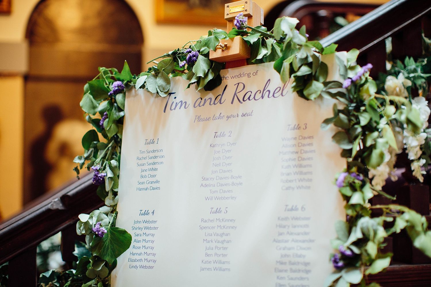 Wedding seating chart display with greenery and elegant typography.