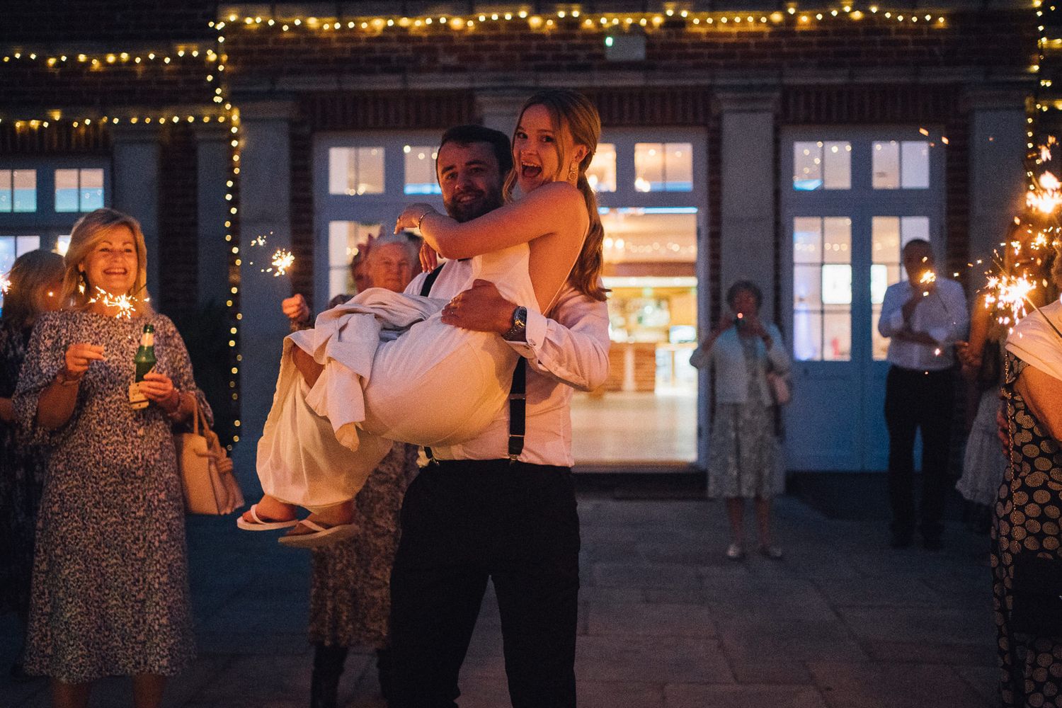 Wedding reception venue lit with string lights and large windows creating a romantic atmosphere.