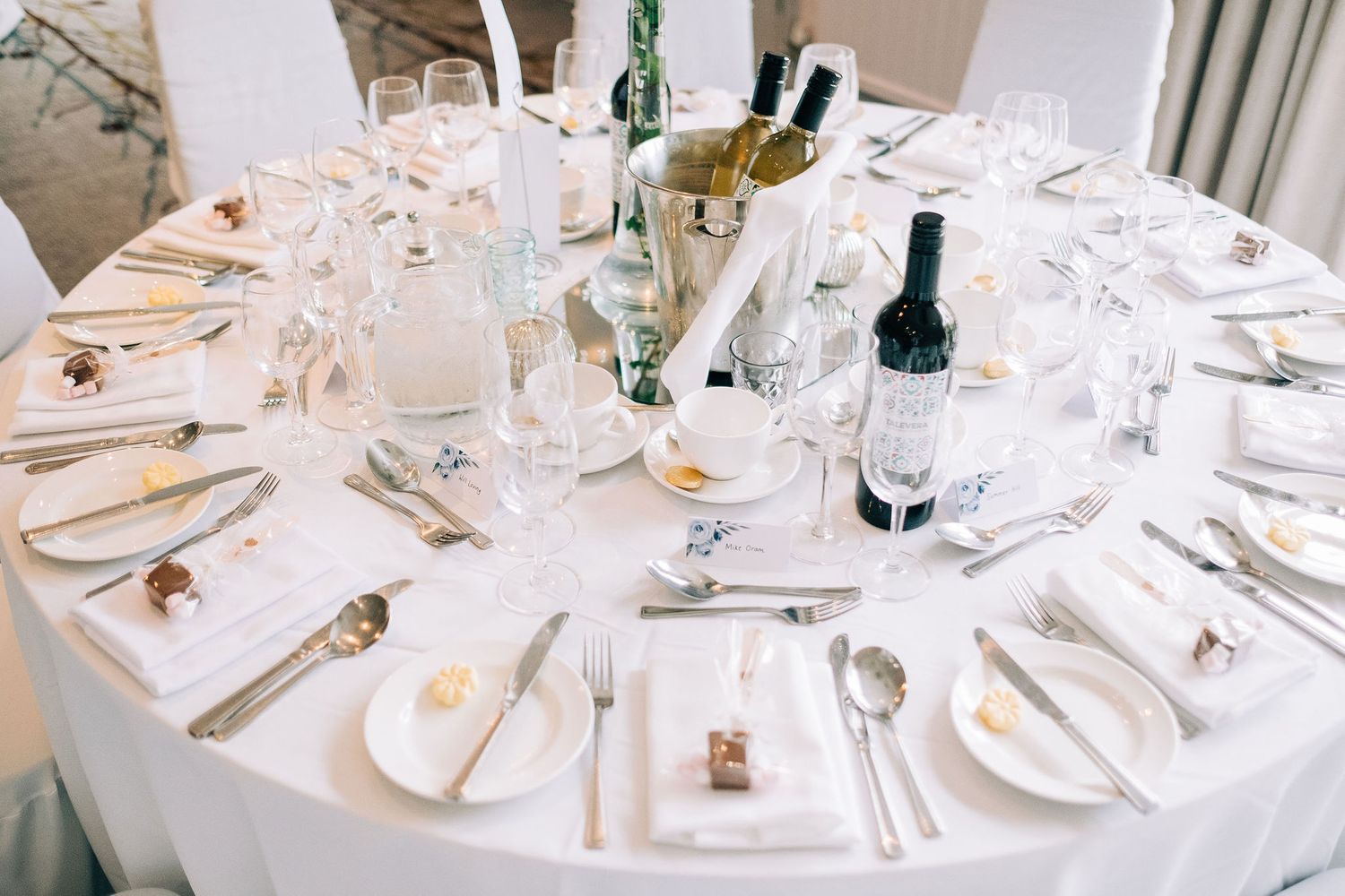 Elegant wedding reception table settings with white linens and wine glasses.