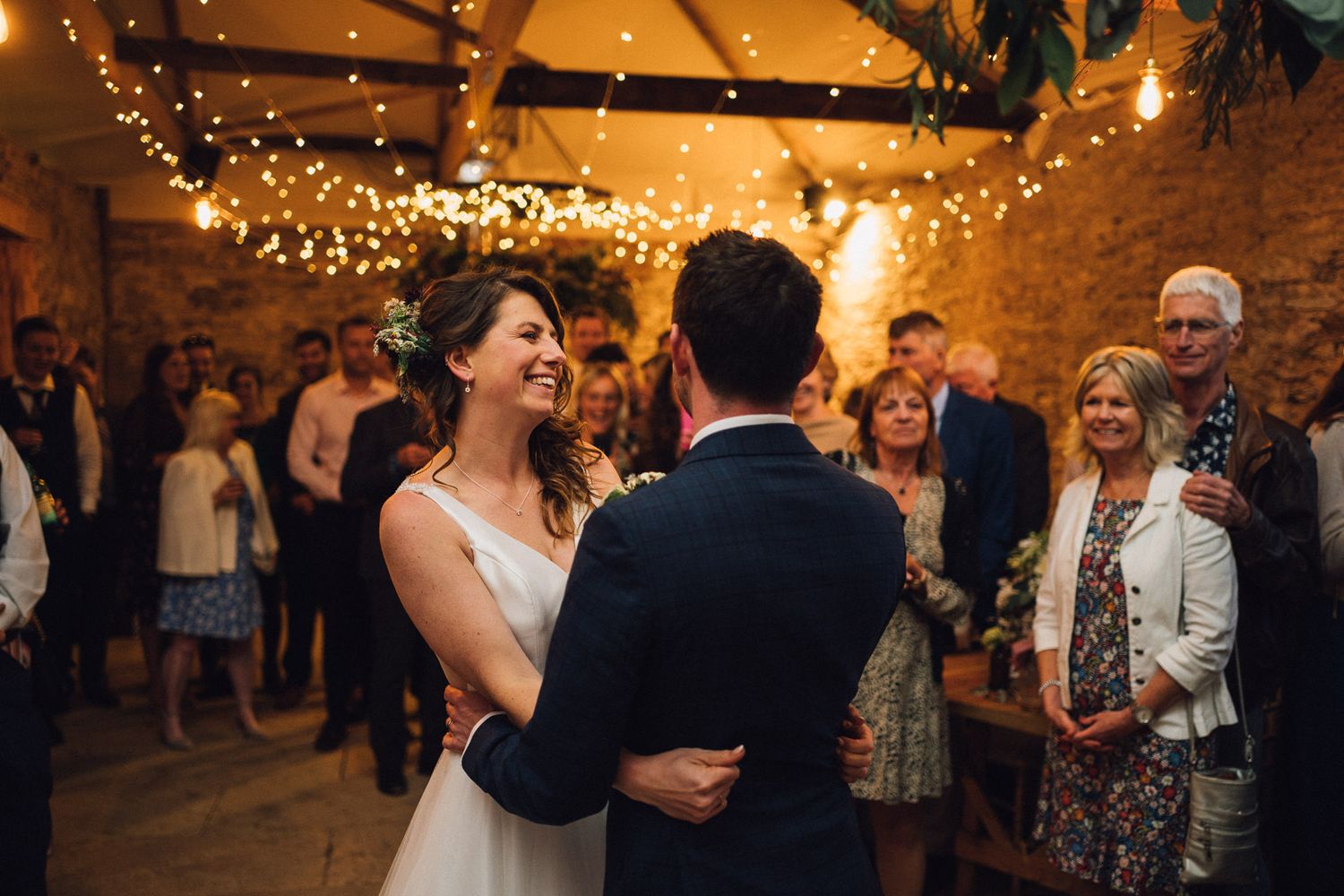 Wedding celebration in full swing at rustic venue with string lights overhead.