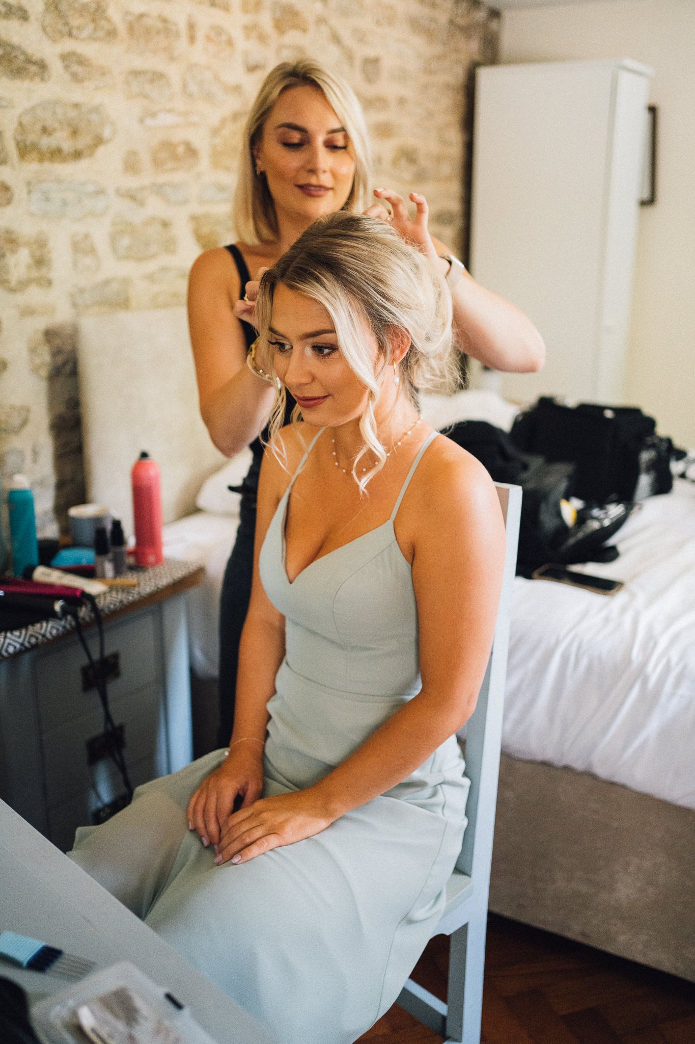 Wedding preparation scene in a rustic stone-walled room with white bedding.
