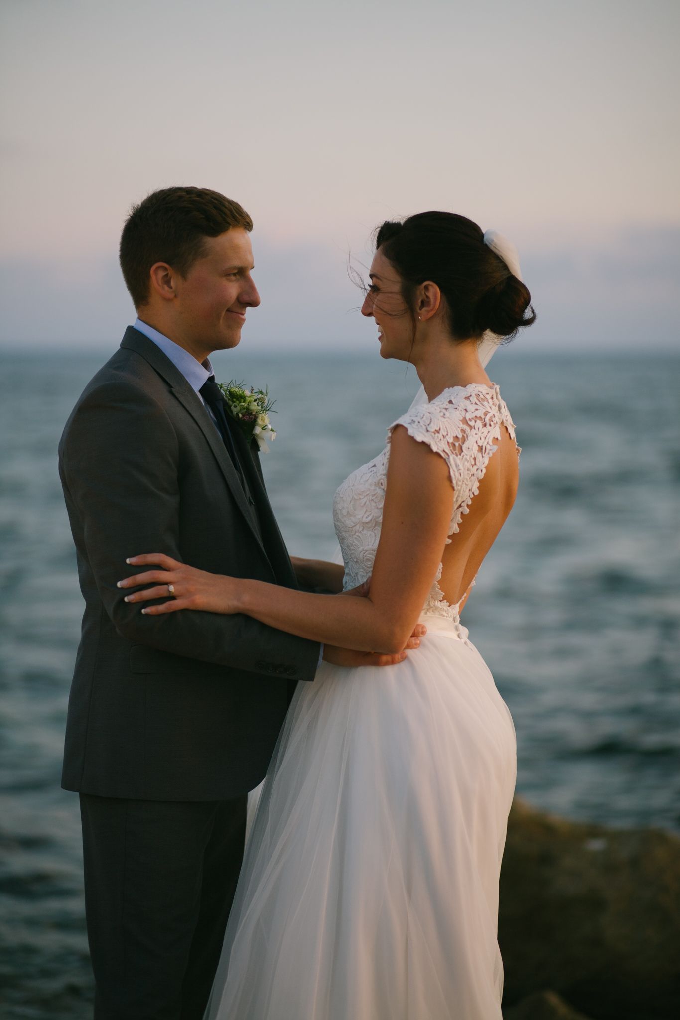 A romantic seaside portrait of a couple sharing a tender moment in their wedding attire.