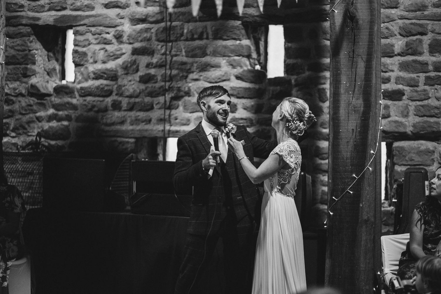 Wedding guests gathered in a historic stone building with wooden beams and ambient lighting.