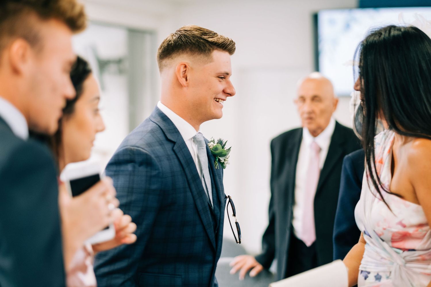 Wedding guests mingling in a modern indoor reception space with bright lighting.