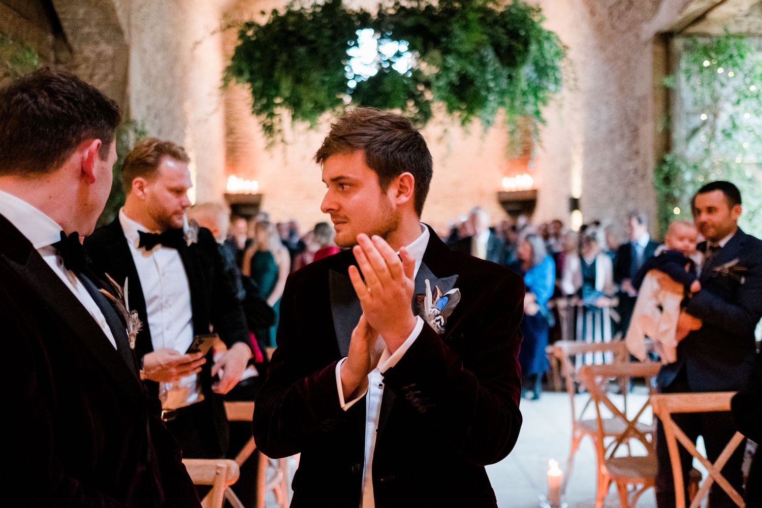 Emotional reactions from wedding attendees in formal attire at a stone venue.