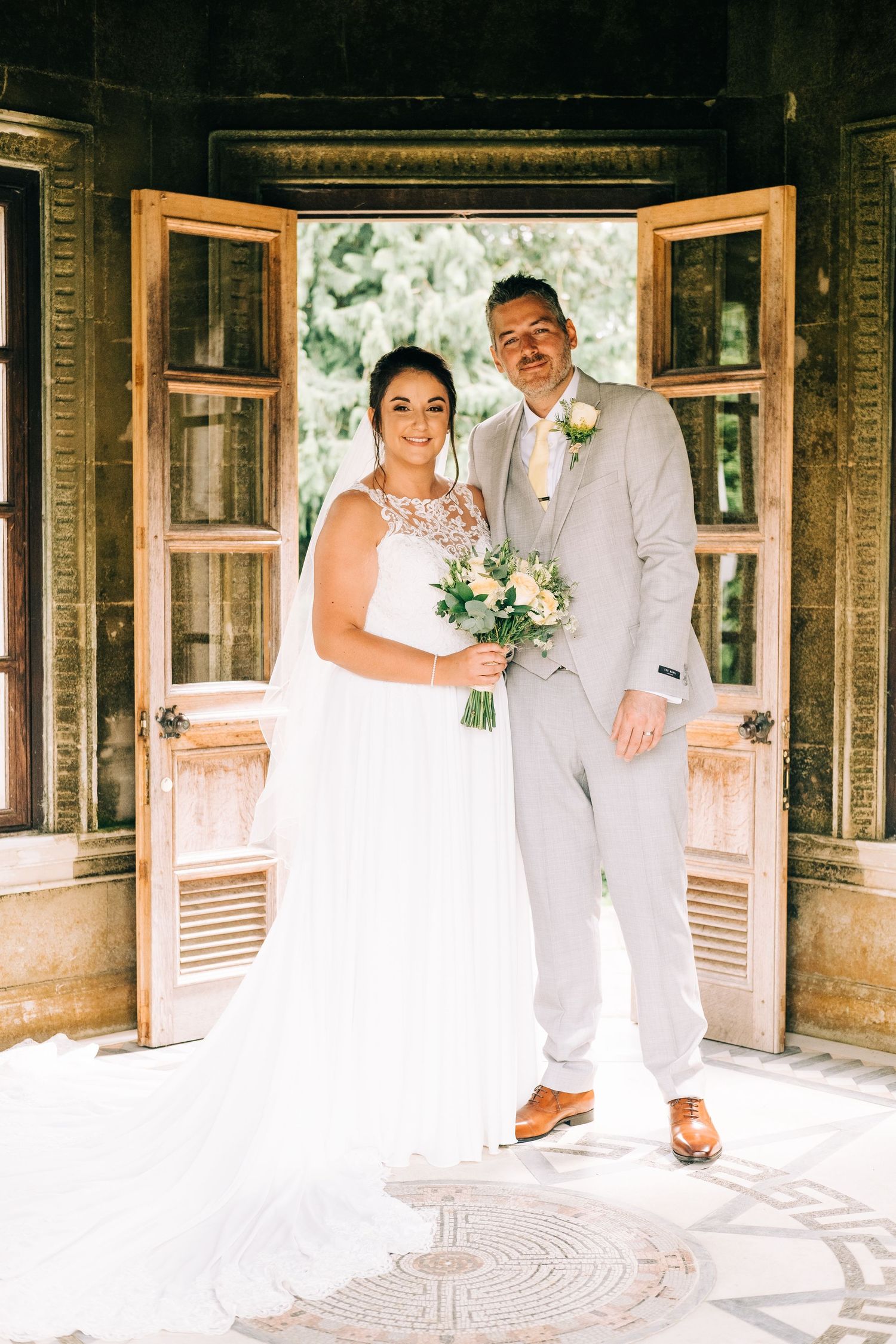 Sunlit wedding portraits taken in a rustic wooden doorway with natural lighting.