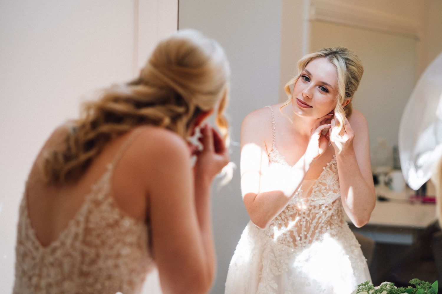 Bridal preparation scene in a bright sunlit room with soft white decor and elegant details.