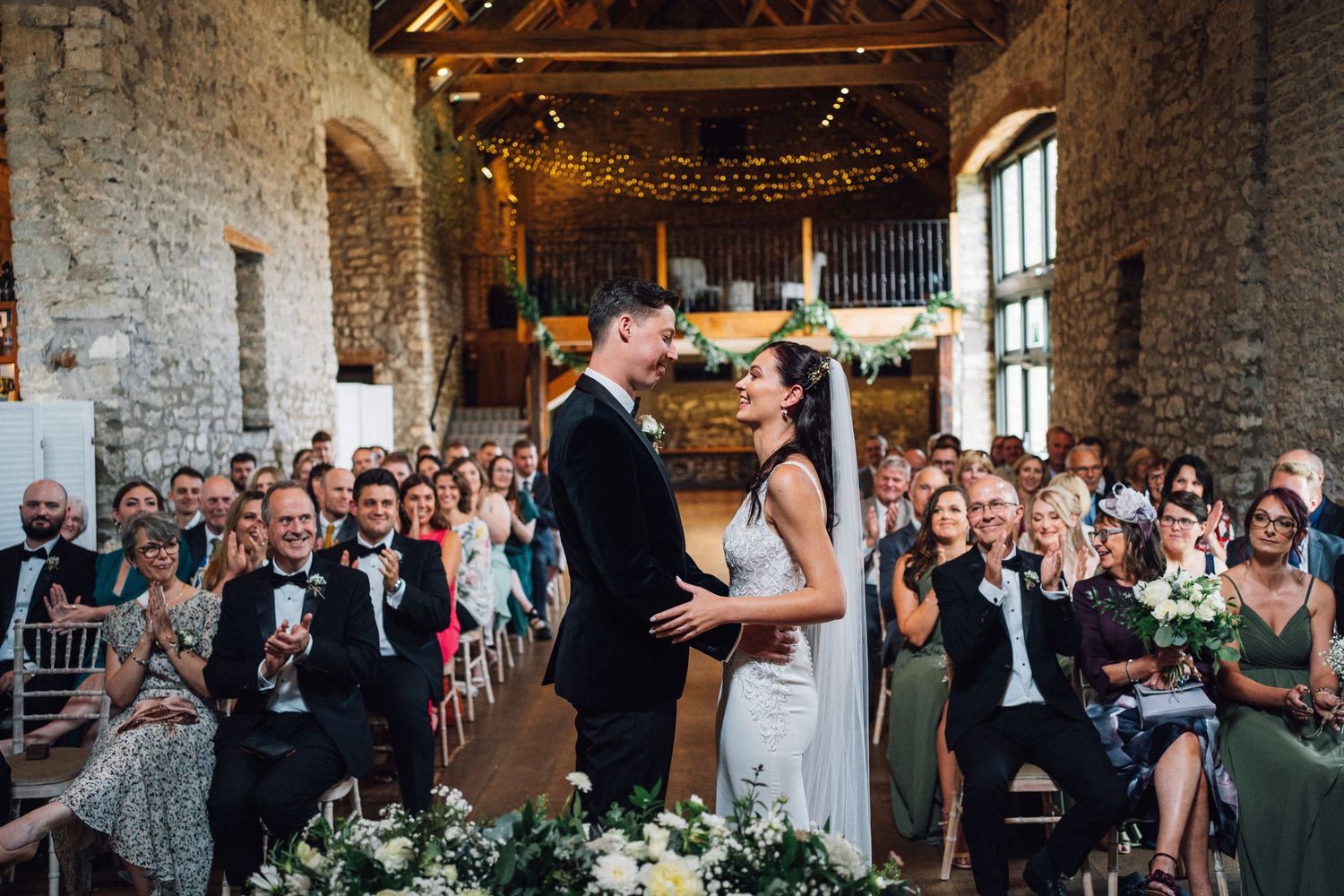 Wedding guests seated for dinner in an elegant rustic venue with exposed brick walls and string lights.