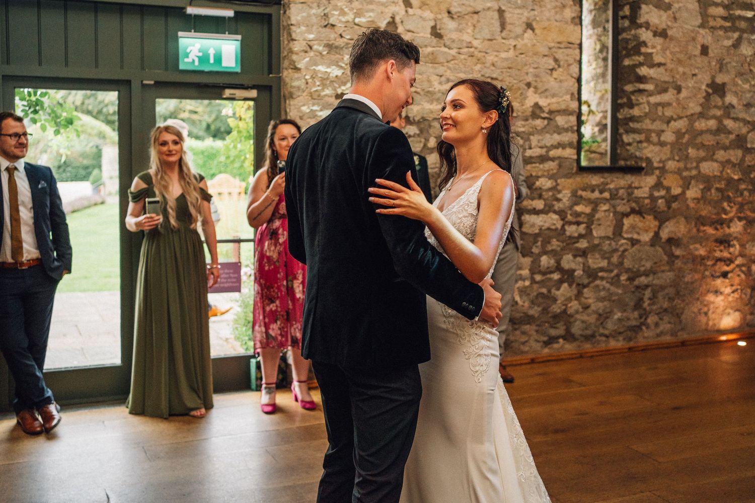 Wedding party dancing and celebrating inside a rustic stone-walled reception venue.