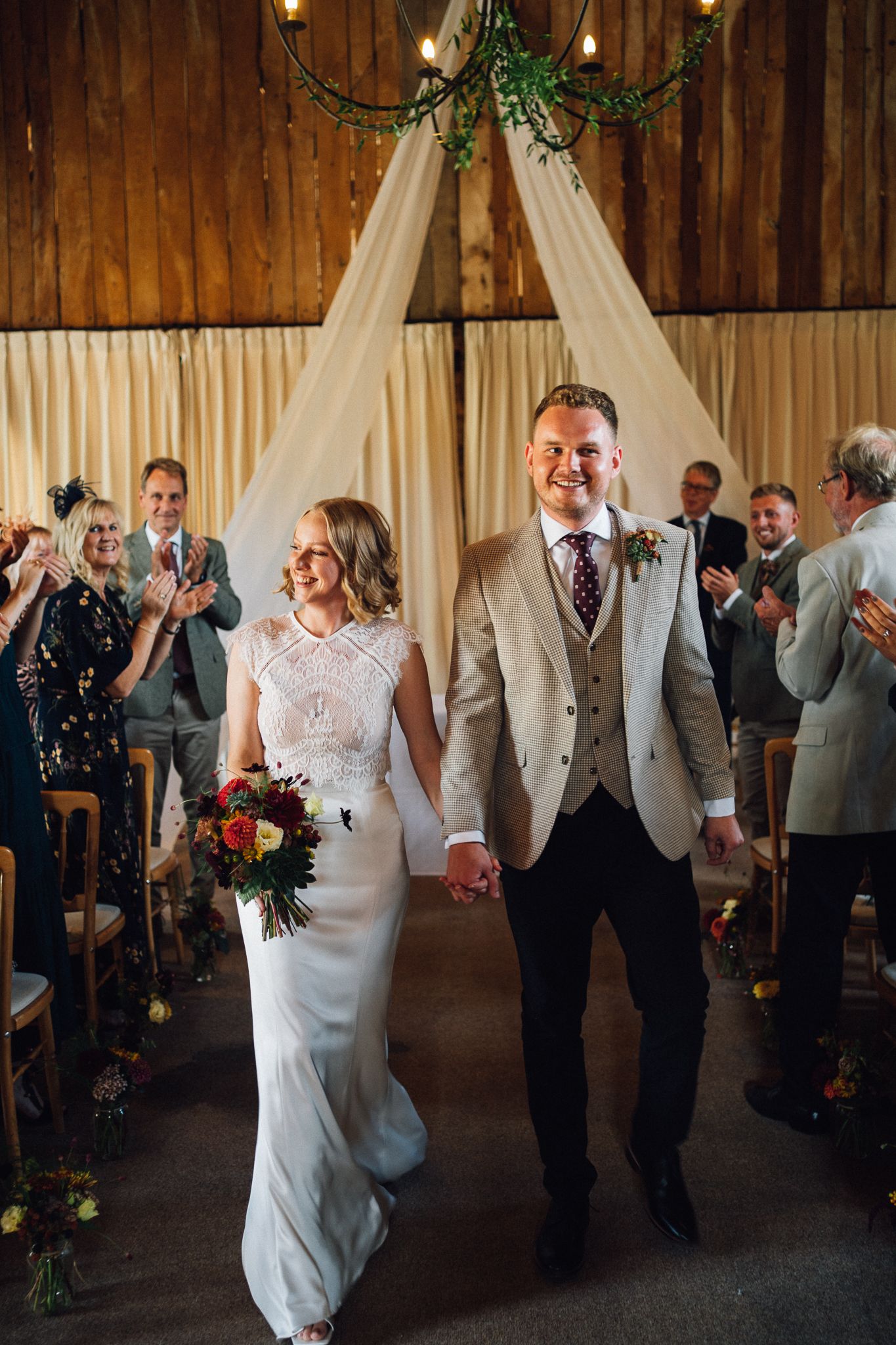 Wedding celebration sequence showing joyful dancing and movement in a rustic barn venue with white drapes and string lights.