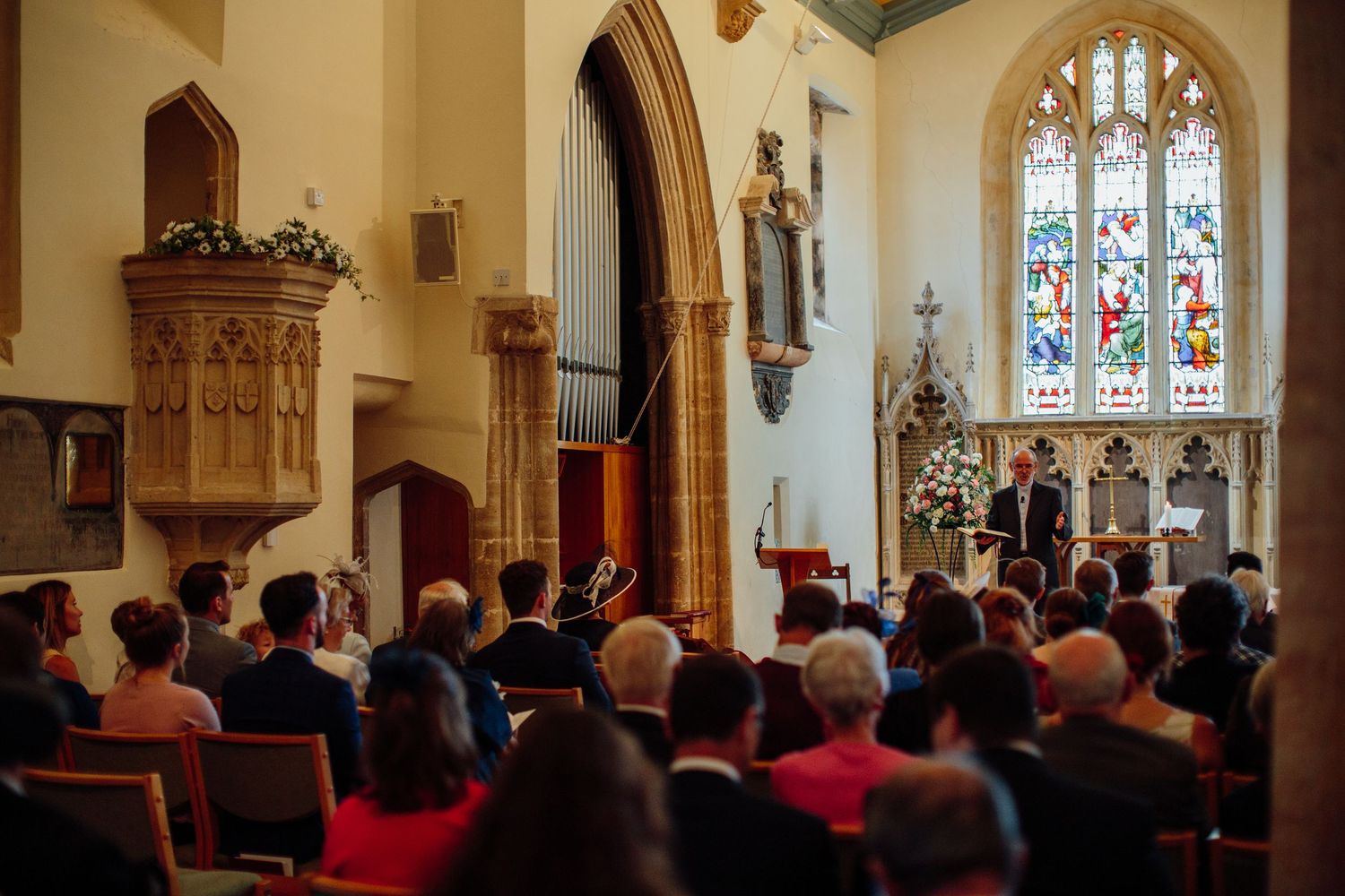 Wedding ceremony taking place in a traditional church with stained glass windows and gathered congregation.