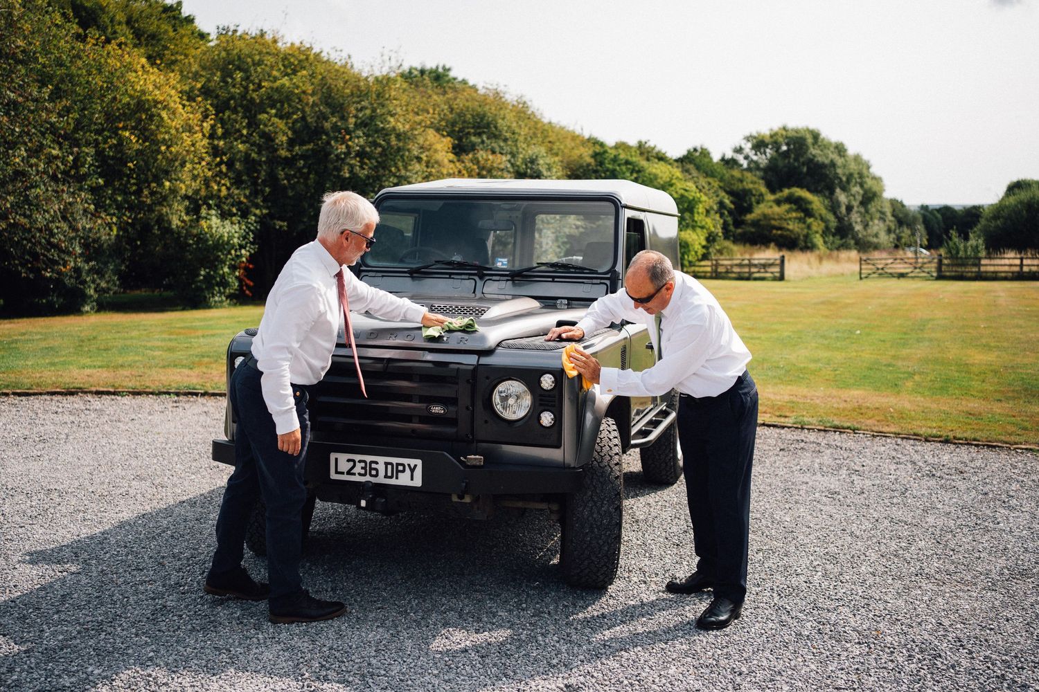 Sequence of photos showing people inspecting and examining a classic black Land Rover vehicle outdoors.
