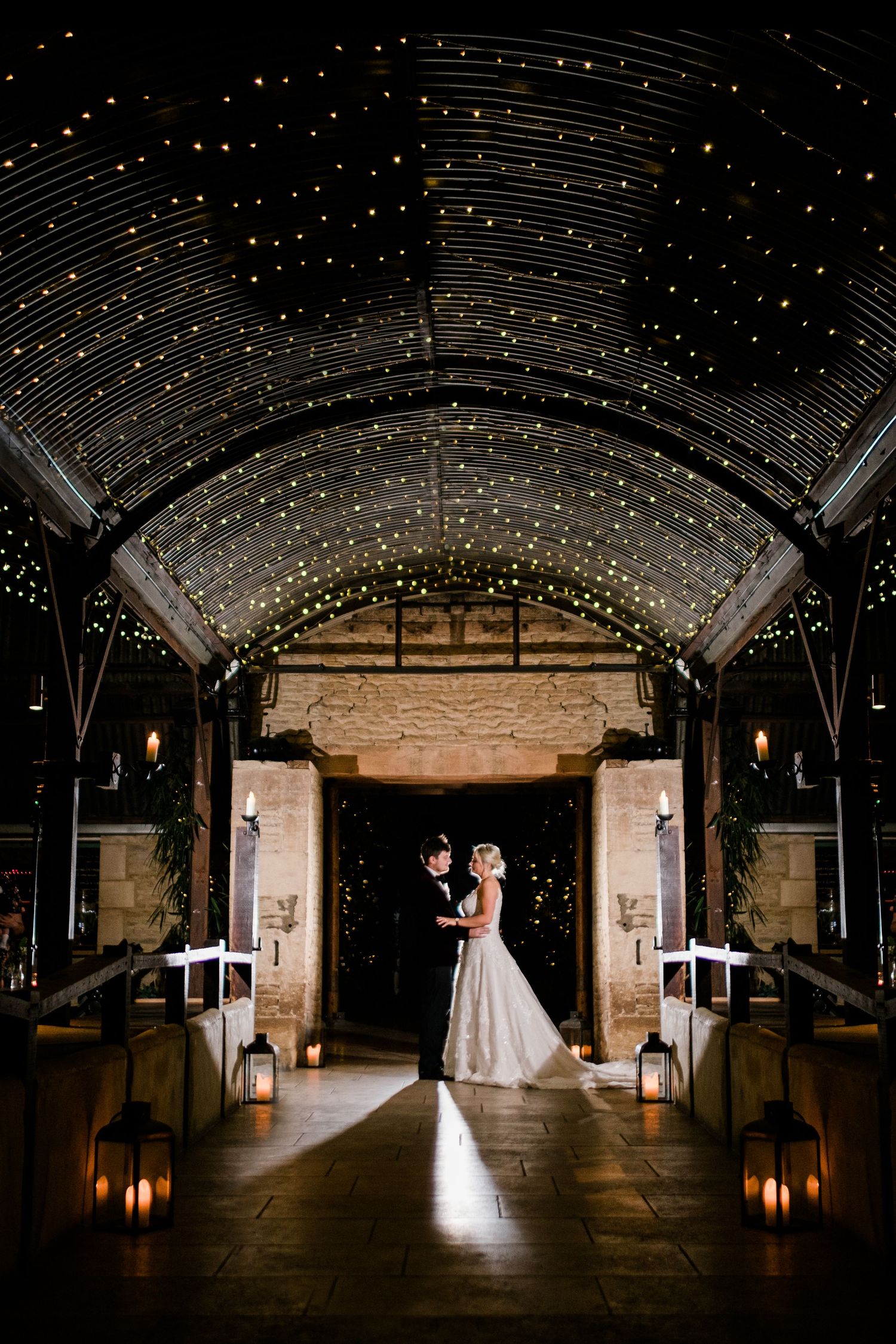 Dramatic wedding photos in a barn with twinkling ceiling lights creating a magical starlit effect.