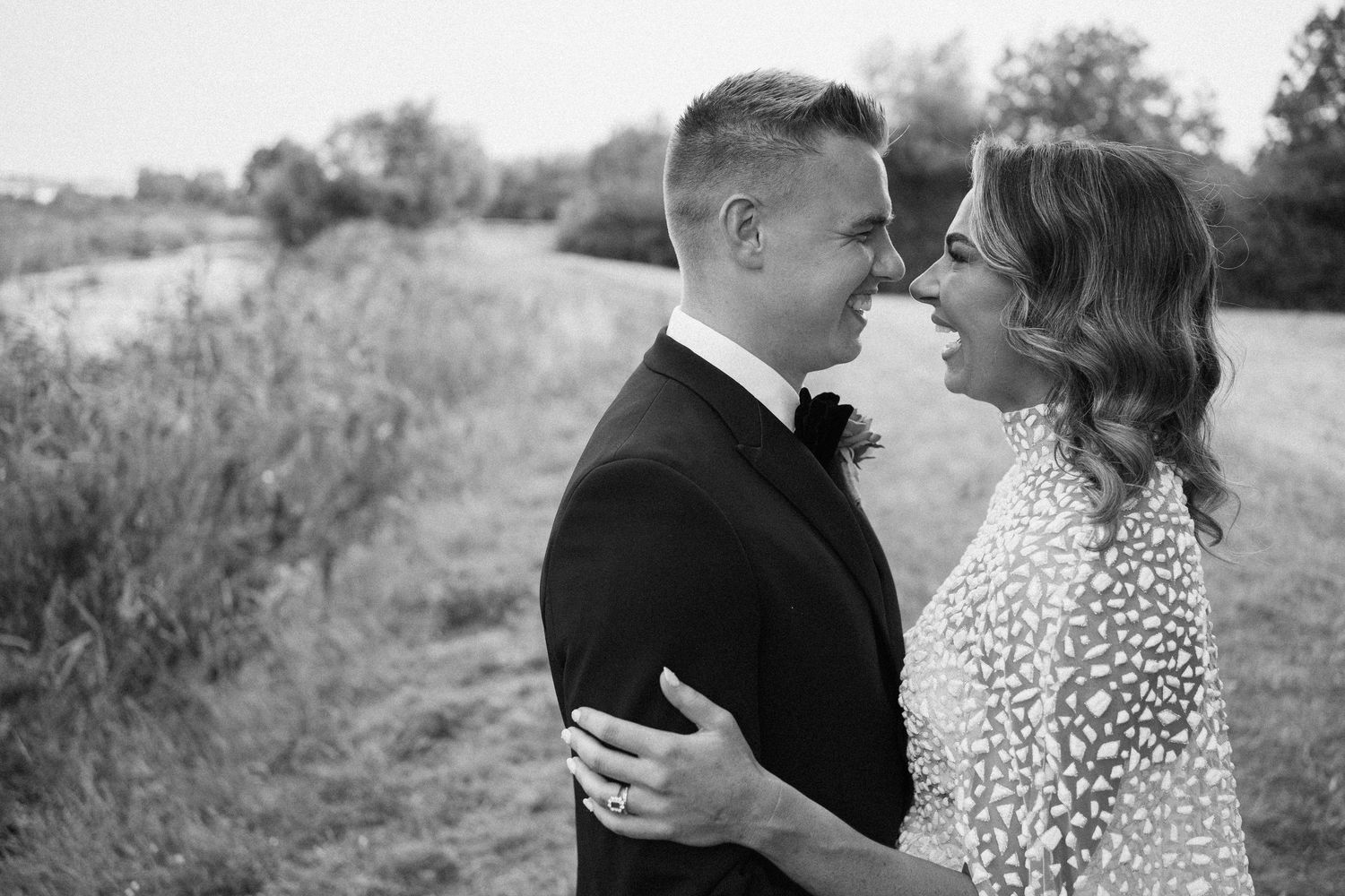 Romantic couple in formal attire embraces in a scenic outdoor setting.