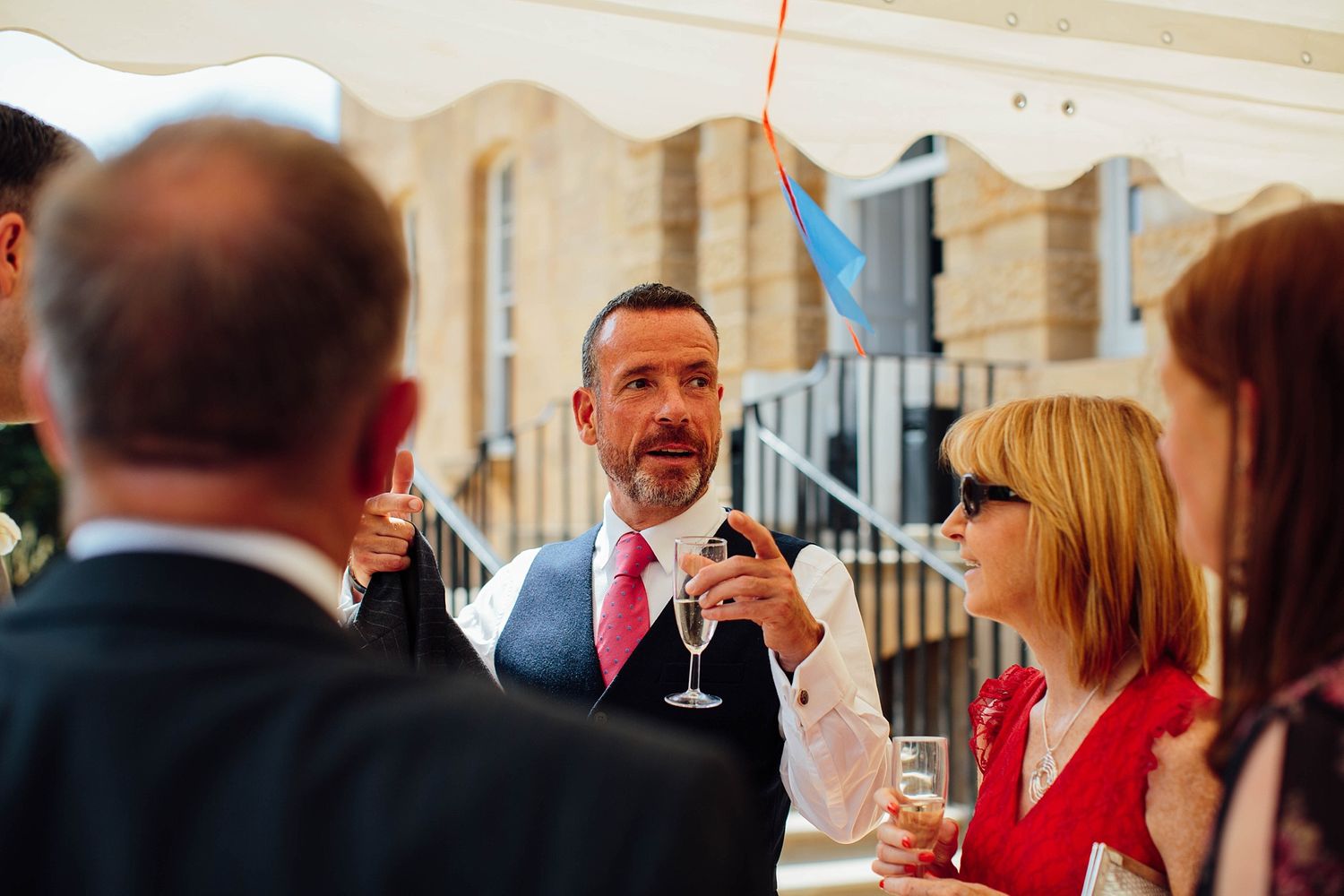 Wedding guests enjoying drinks and conversation during outdoor reception.