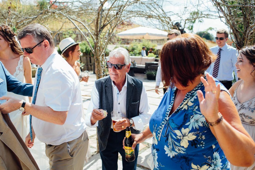 Guests enjoying drinks and conversation during an outdoor daytime celebration.
