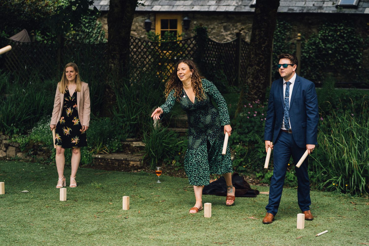 Wedding guests mingling on grass lawn during outdoor garden reception.