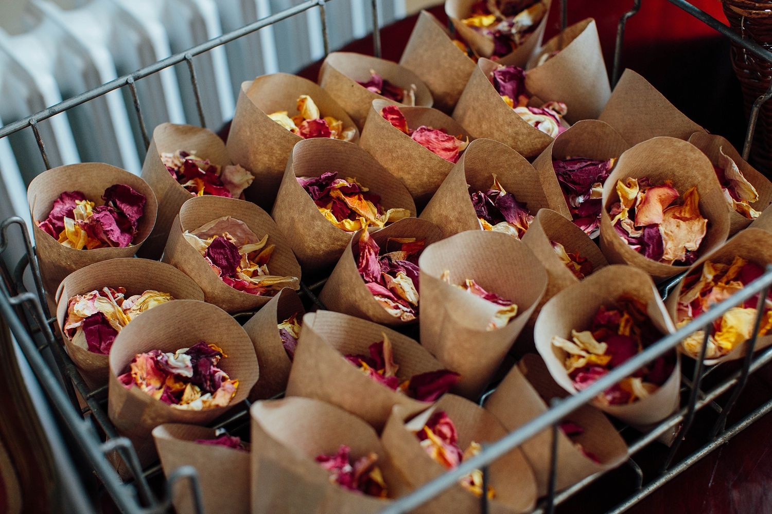 Rows of beautifully arranged flower petals in paper cones for wedding ceremony.