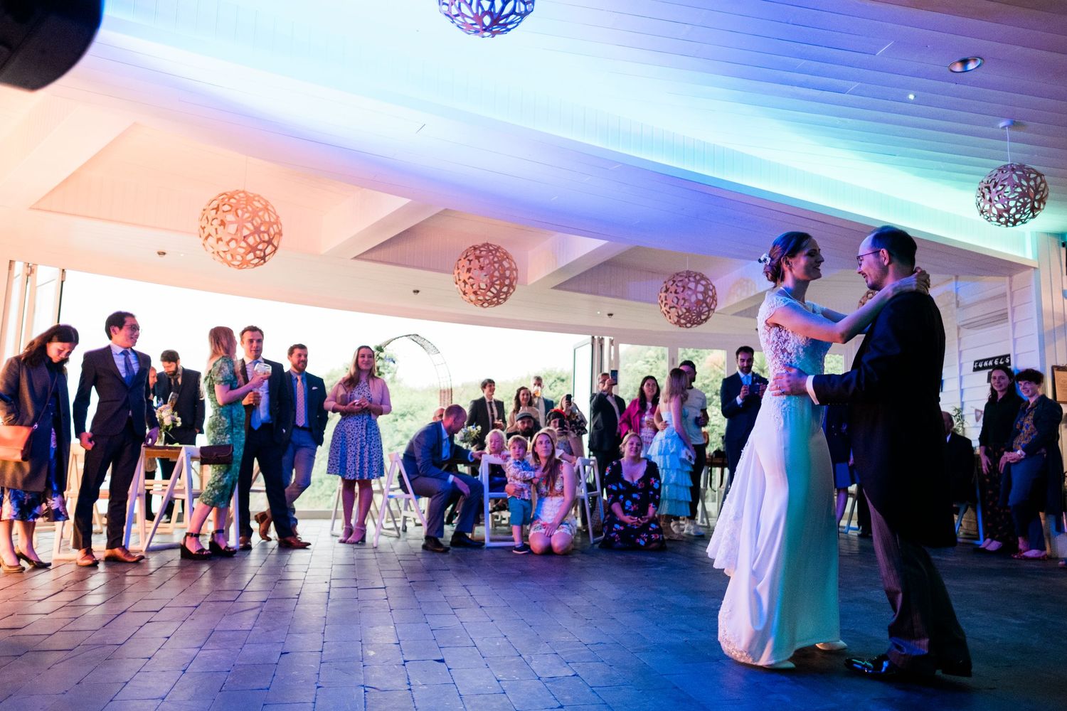 Wedding reception venue decorated with glowing disco balls and blue lighting for an elegant evening celebration.