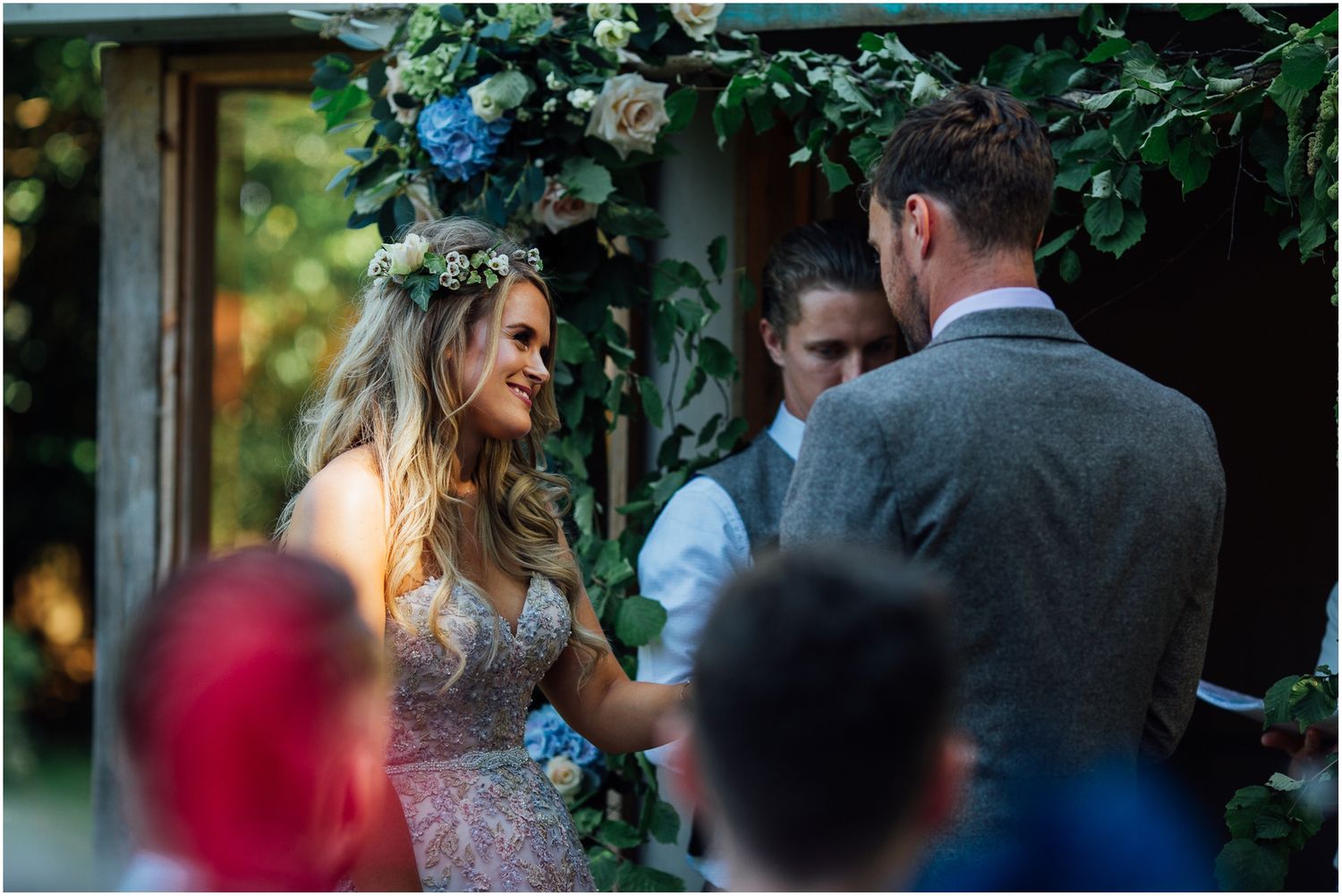 Romantic wedding couple embraces in a garden setting with lush greenery in the background.