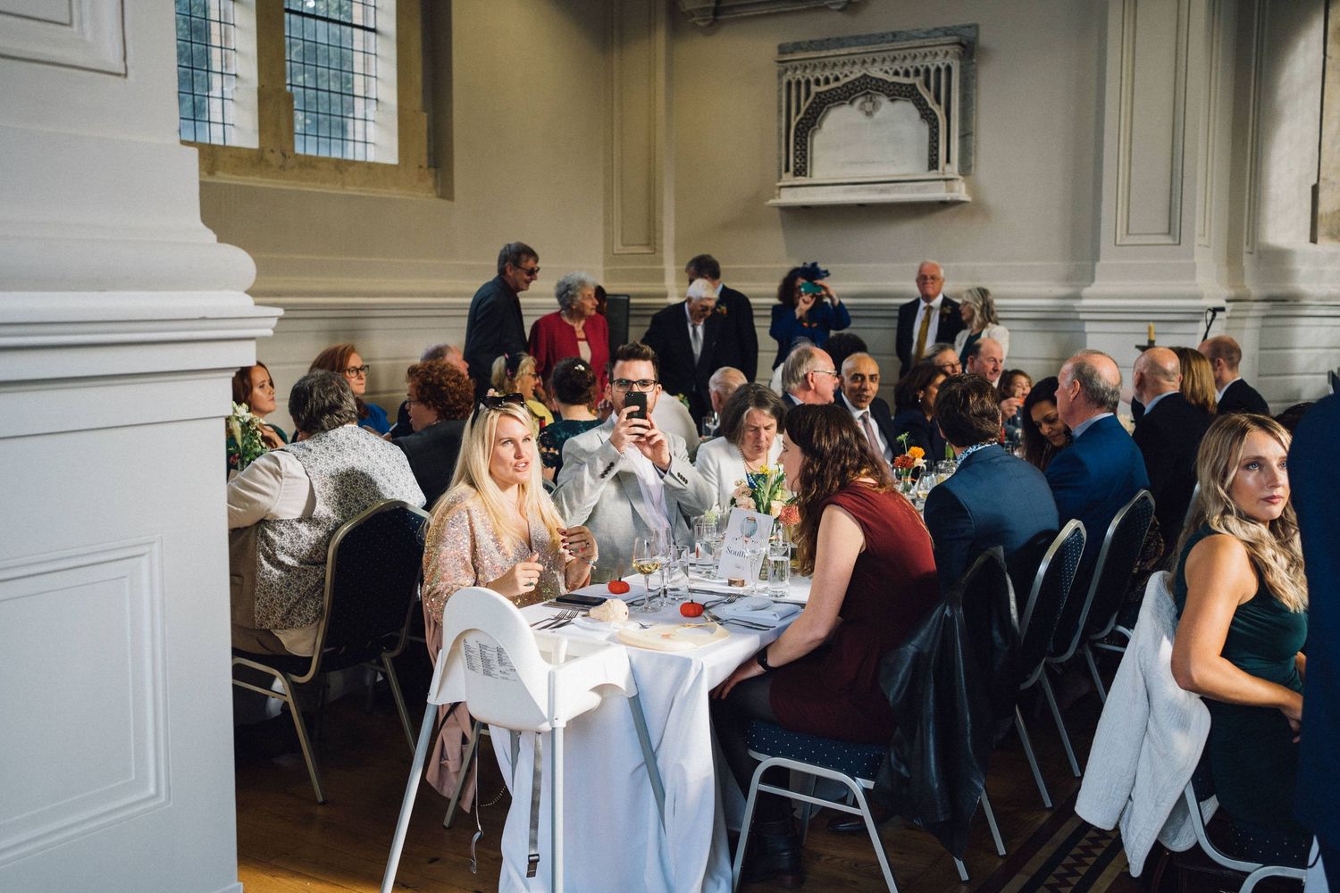 Wedding guests seated at long tables during an indoor reception celebration.