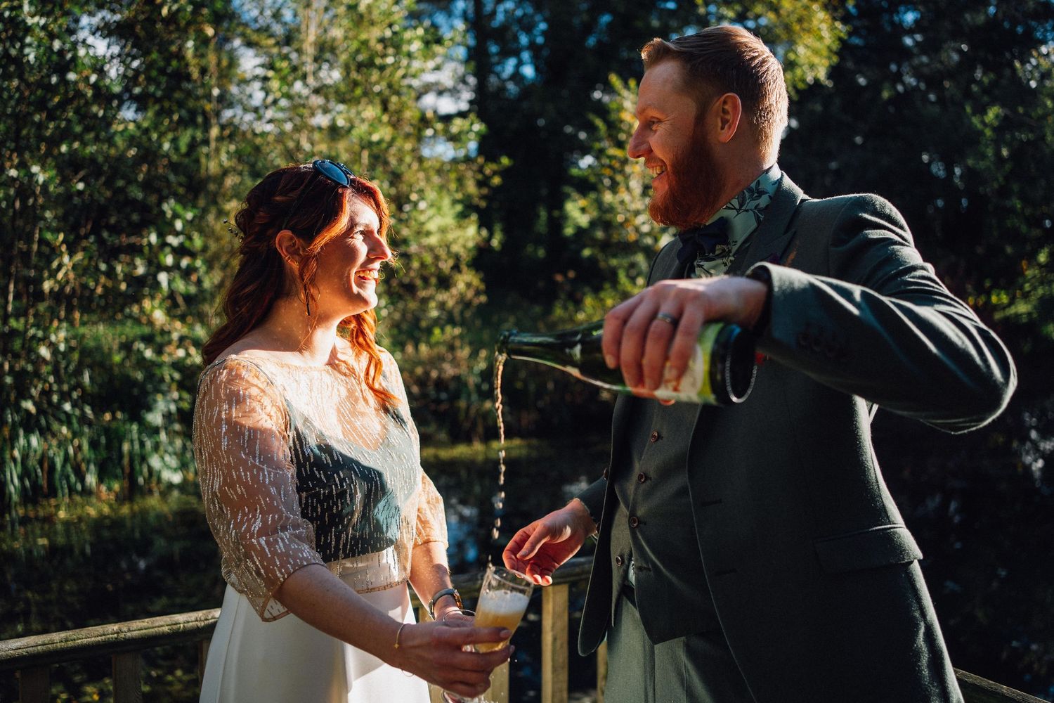 Guests gathered outdoors for a wedding celebration with trees and natural lighting in the background.