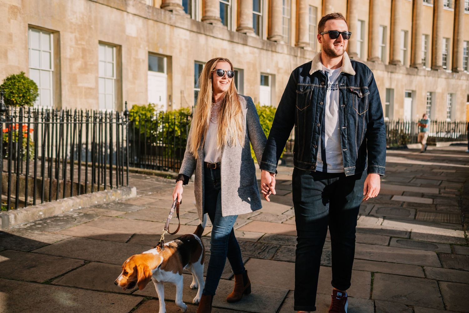 Couple walking together on a sunny day along historic Georgian architecture in Bath, England.