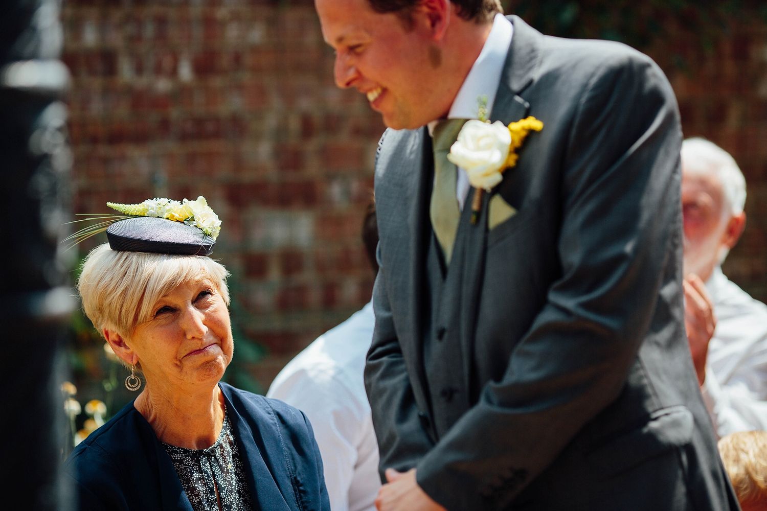 Wedding guests share emotional reactions during an outdoor ceremony.